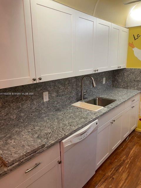 kitchen featuring white cabinetry, dishwasher, sink, light stone counters, and dark wood-type flooring