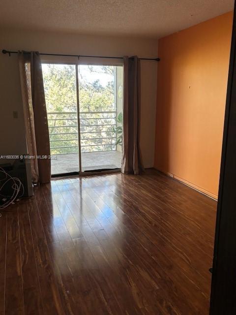 empty room with dark hardwood / wood-style floors and a textured ceiling