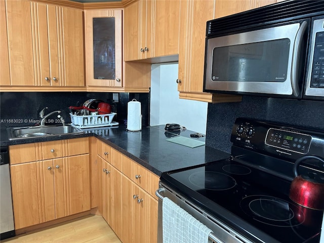 kitchen with appliances with stainless steel finishes, decorative backsplash, sink, and light hardwood / wood-style floors