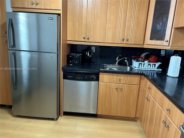 kitchen with light hardwood / wood-style flooring, stainless steel appliances, sink, and backsplash