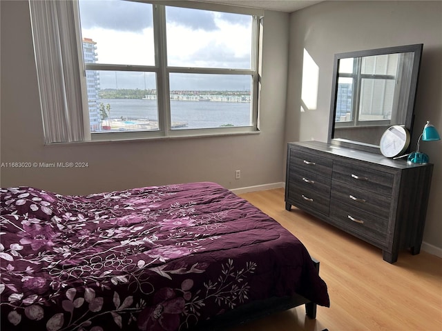 bedroom featuring a water view and light hardwood / wood-style floors