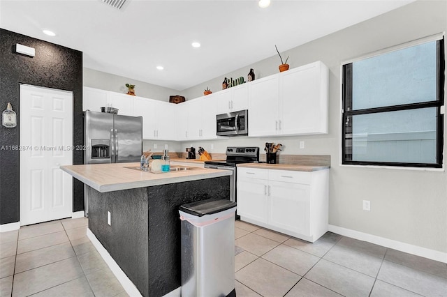 kitchen featuring white cabinetry, a kitchen island with sink, light tile patterned flooring, and stainless steel appliances