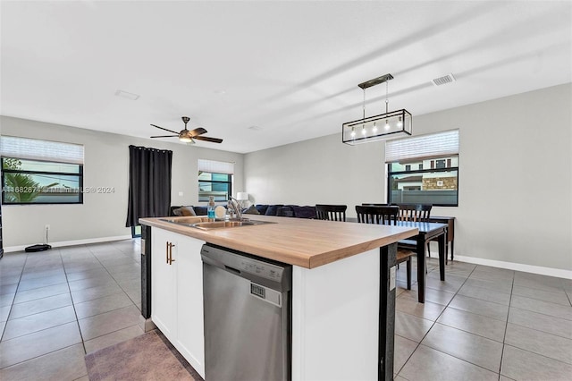 kitchen with a wealth of natural light, a center island with sink, hanging light fixtures, and stainless steel dishwasher