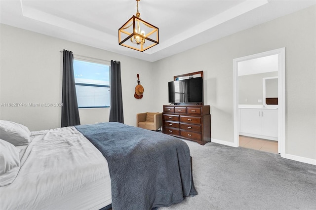 carpeted bedroom featuring connected bathroom, a notable chandelier, and a raised ceiling