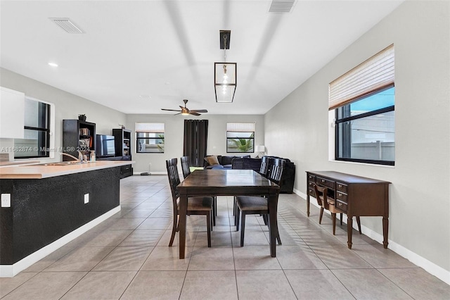 tiled dining space with ceiling fan and sink