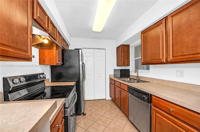 kitchen featuring appliances with stainless steel finishes, a sink, light countertops, under cabinet range hood, and light tile patterned flooring