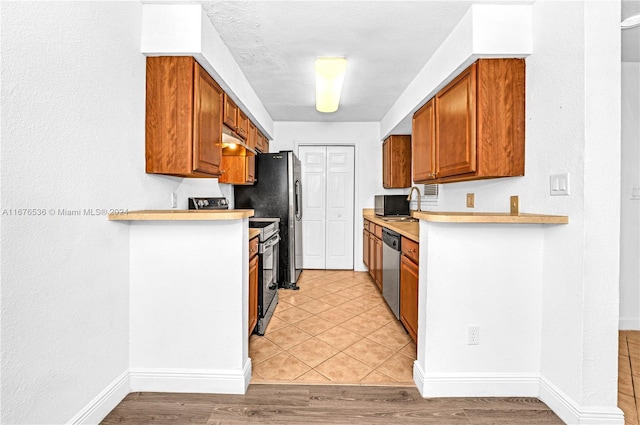 kitchen with light hardwood / wood-style flooring, stainless steel appliances, and kitchen peninsula