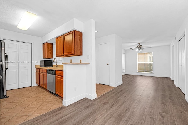 kitchen featuring brown cabinets, ceiling fan, light countertops, light wood-style flooring, and stainless steel appliances