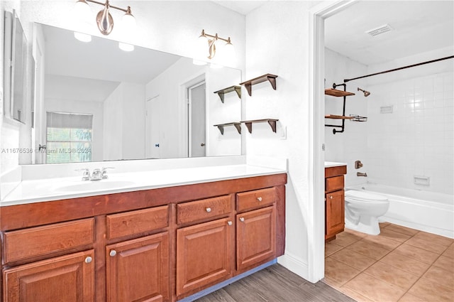 full bathroom with toilet, tiled shower / bath, vanity, and wood-type flooring