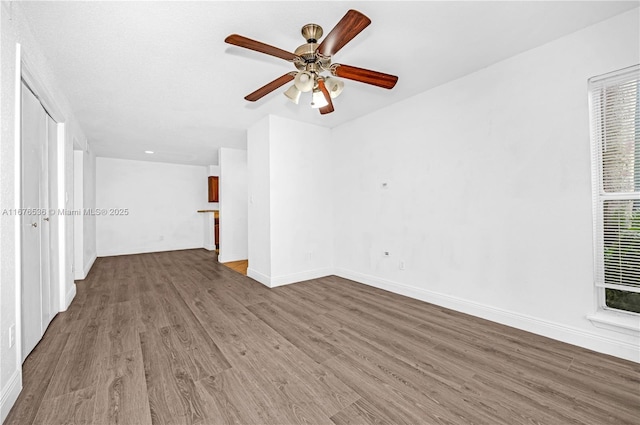 spare room with baseboards, ceiling fan, and wood finished floors