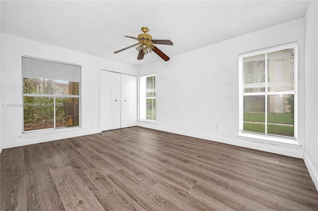 empty room with ceiling fan, a healthy amount of sunlight, and wood finished floors