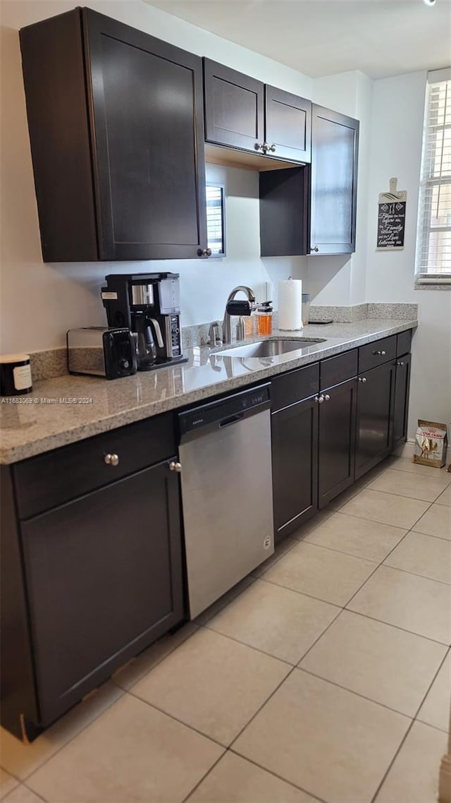 kitchen featuring sink, light tile patterned floors, light stone countertops, and dishwasher