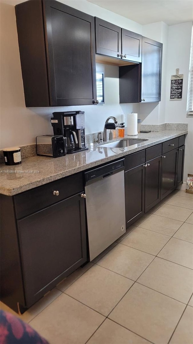 kitchen featuring dark brown cabinetry, stainless steel dishwasher, sink, and light tile patterned floors