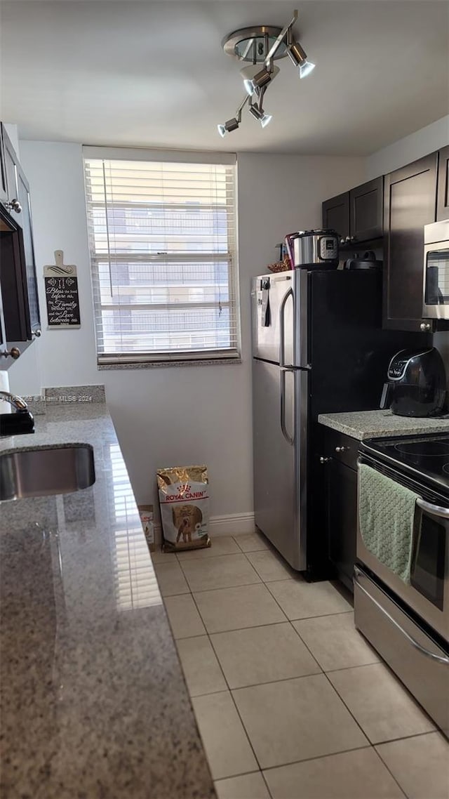 kitchen featuring sink, light stone counters, stainless steel appliances, and light tile patterned floors