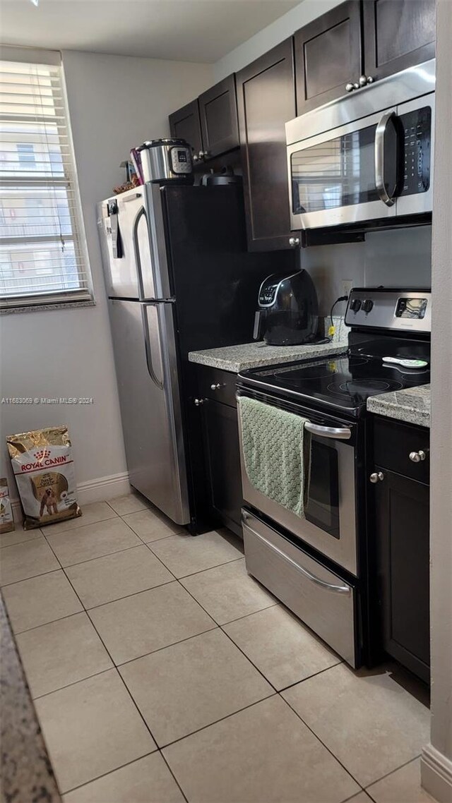 kitchen featuring light stone countertops, stainless steel appliances, and light tile patterned floors