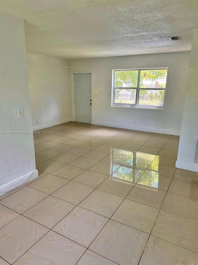 tiled spare room with a textured ceiling