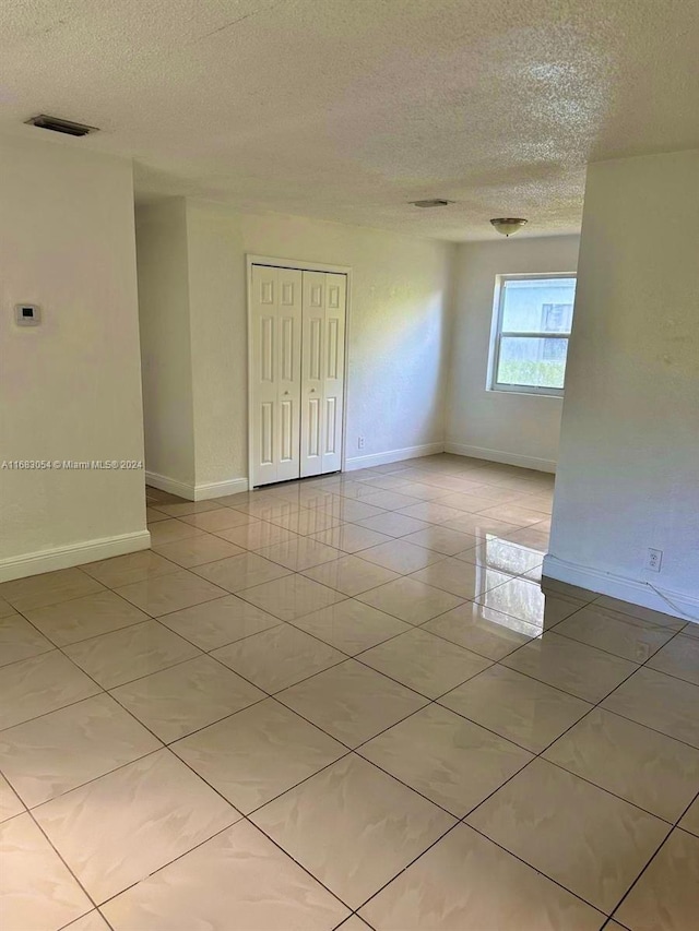 empty room featuring light tile patterned flooring and a textured ceiling