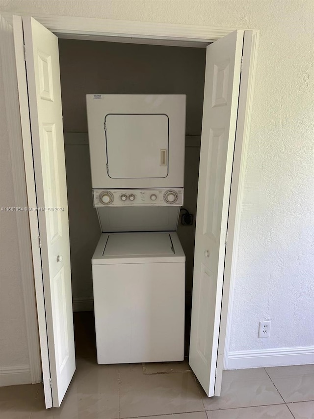 laundry room with light tile patterned flooring and stacked washing maching and dryer