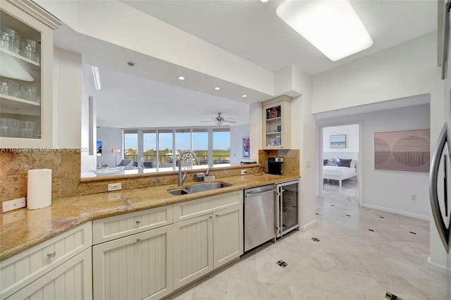 kitchen featuring cream cabinetry, stainless steel dishwasher, sink, and vaulted ceiling