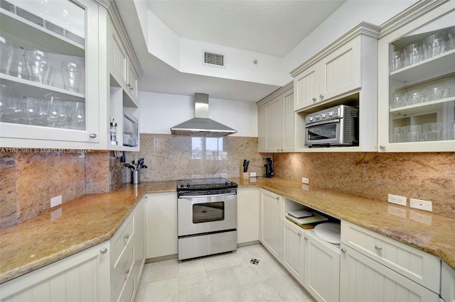 kitchen with wall chimney exhaust hood, backsplash, light stone counters, and stainless steel electric range oven