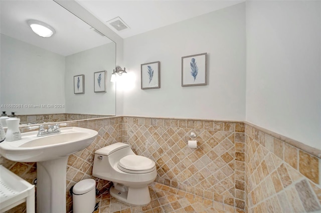 bathroom featuring tile walls and toilet