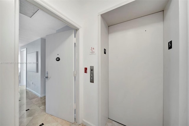 hallway featuring light tile patterned flooring and elevator