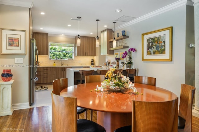 dining area with ornamental molding, sink, and dark hardwood / wood-style floors