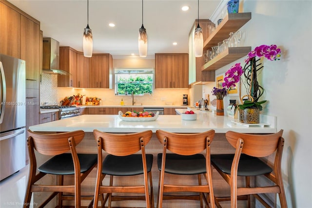 kitchen featuring stainless steel appliances, wall chimney exhaust hood, a breakfast bar, and kitchen peninsula