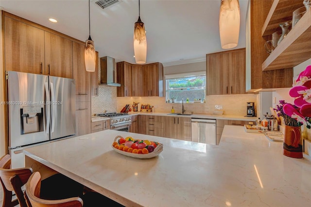 kitchen with stainless steel appliances, decorative light fixtures, decorative backsplash, kitchen peninsula, and wall chimney exhaust hood