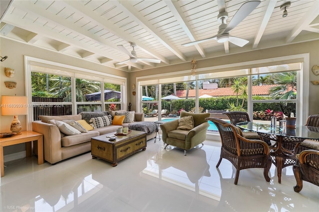 sunroom featuring ceiling fan and beam ceiling