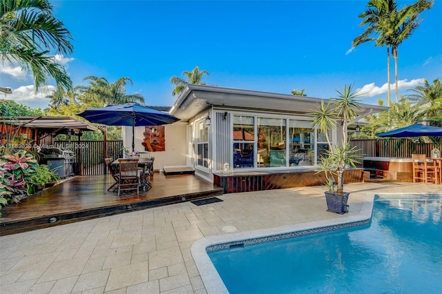 rear view of property featuring a pool with hot tub and a patio area