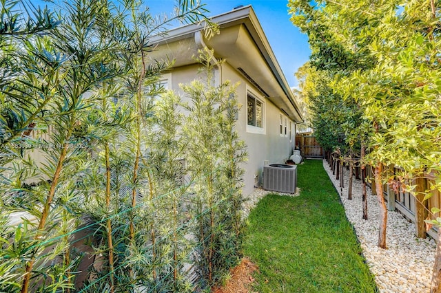 view of side of property featuring central air condition unit and a lawn