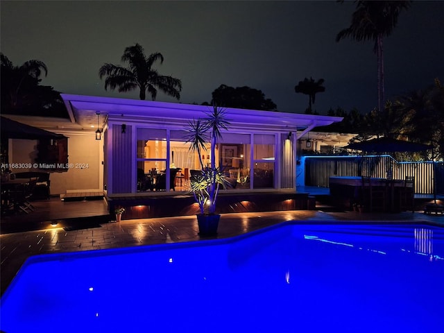 pool at night featuring a deck