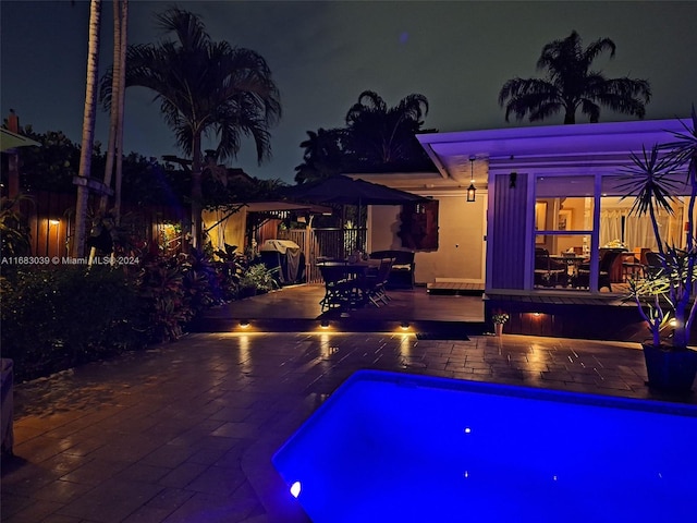 pool at night featuring a patio