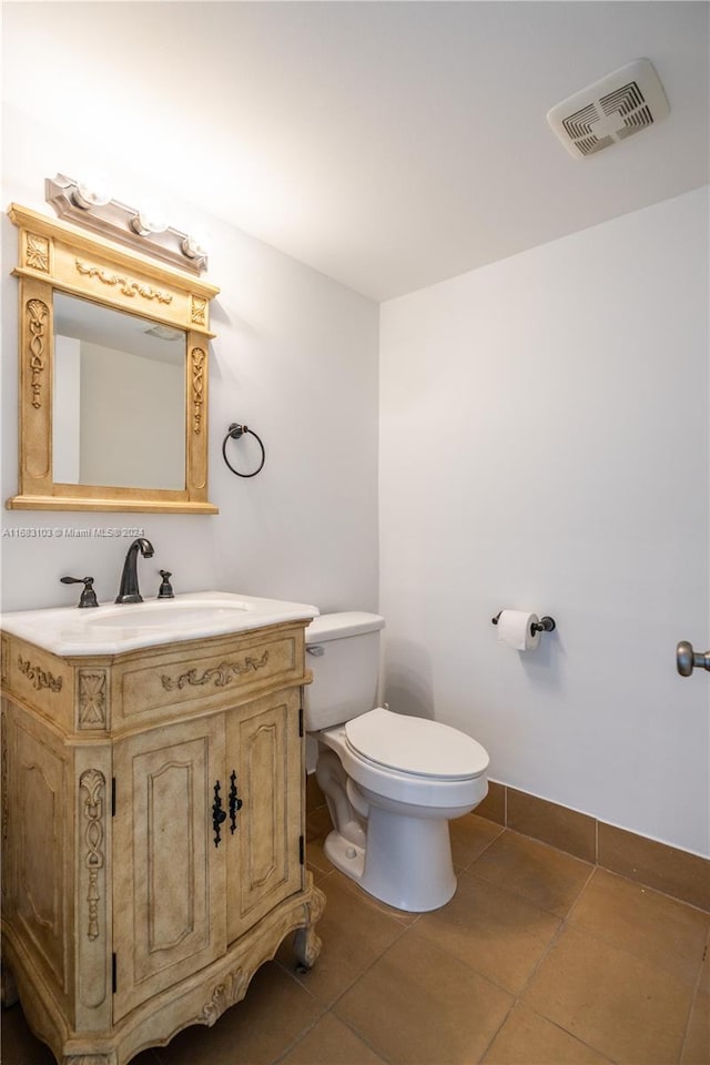 bathroom with toilet, vanity, and tile patterned flooring