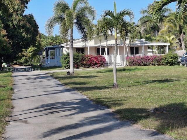 view of front of property featuring a sunroom, cooling unit, and a front yard