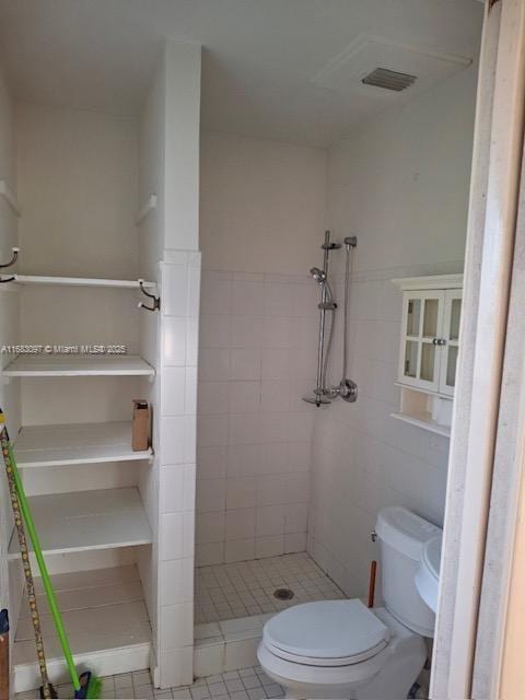 bathroom with a tile shower, tile patterned flooring, and toilet