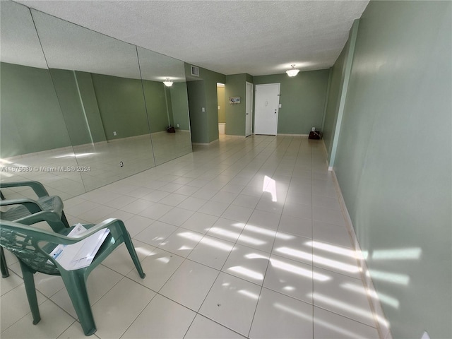 tiled empty room featuring a textured ceiling