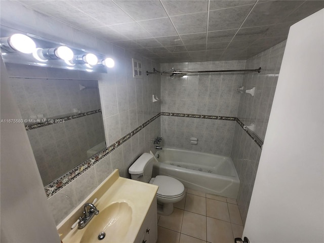 full bathroom with tile walls, toilet, vanity, tiled shower / bath combo, and tile patterned floors