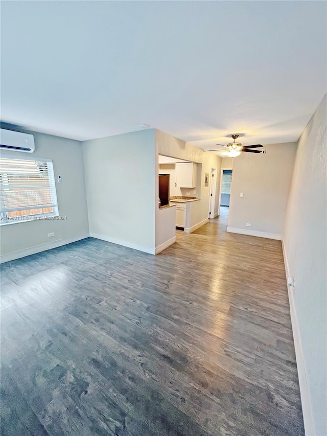 unfurnished living room with a wall unit AC, dark hardwood / wood-style floors, and ceiling fan