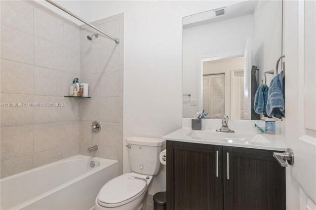 full bathroom with tiled shower / bath, vanity, and toilet