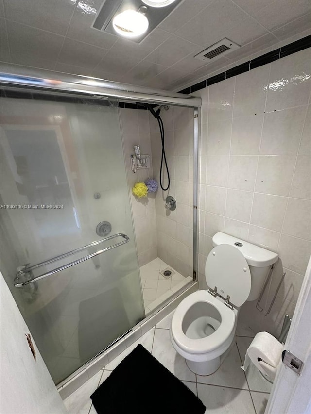 bathroom featuring tile walls, tile patterned floors, toilet, and an enclosed shower