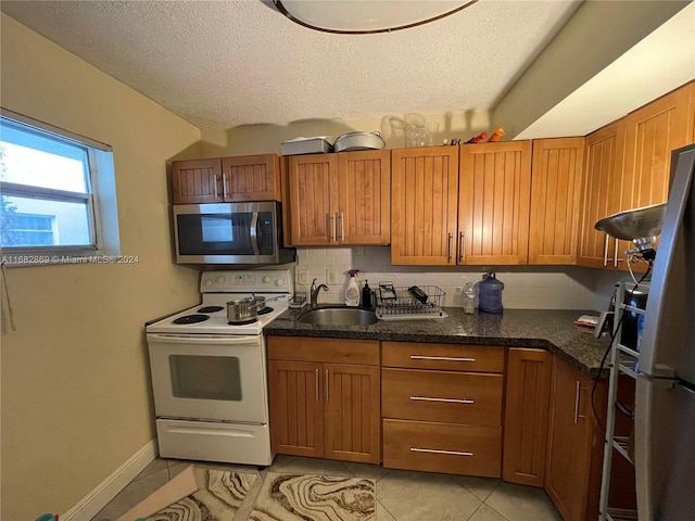 kitchen with sink, a textured ceiling, light tile patterned flooring, and stainless steel appliances