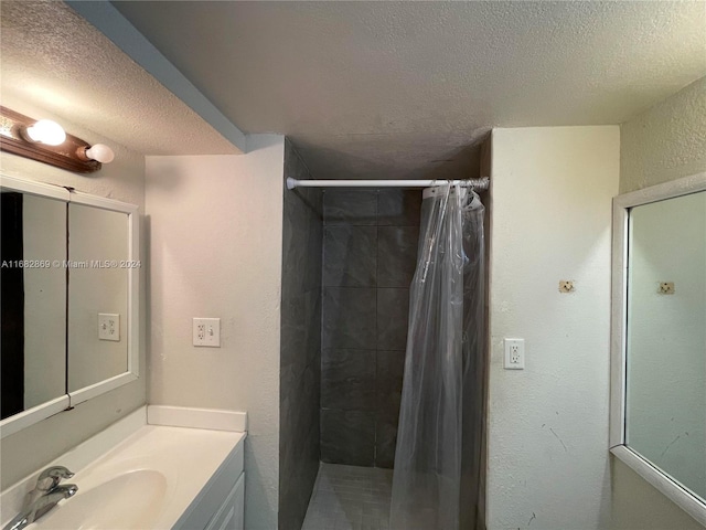 bathroom with vanity, a textured ceiling, and walk in shower