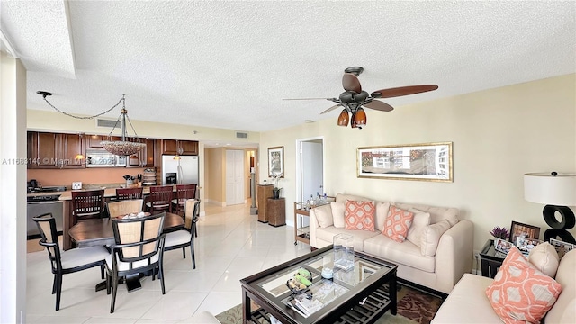 living room with light tile patterned flooring, ceiling fan, and a textured ceiling