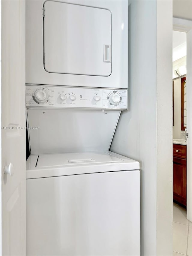 laundry area featuring stacked washer / dryer and light tile patterned floors