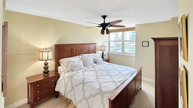 bedroom featuring ceiling fan, a textured ceiling, and light carpet