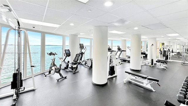 workout area featuring a paneled ceiling and a water view