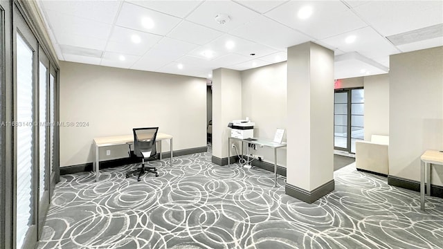 carpeted office with a paneled ceiling, a healthy amount of sunlight, and built in desk