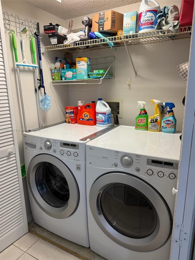 laundry room with separate washer and dryer, light tile patterned flooring, and a textured ceiling